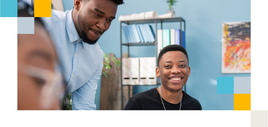 Colleague supports a smiling teammate in a modern office, introducing a new idea.