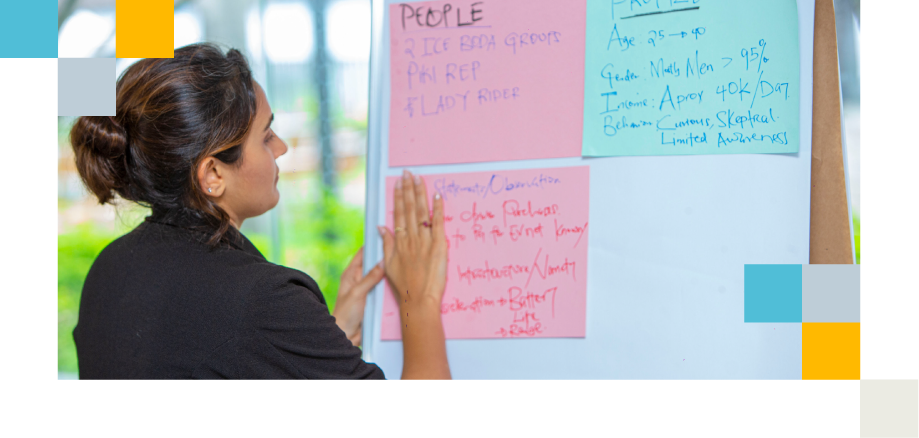 Women stands in front of flipchart and writes something about customer analysis.